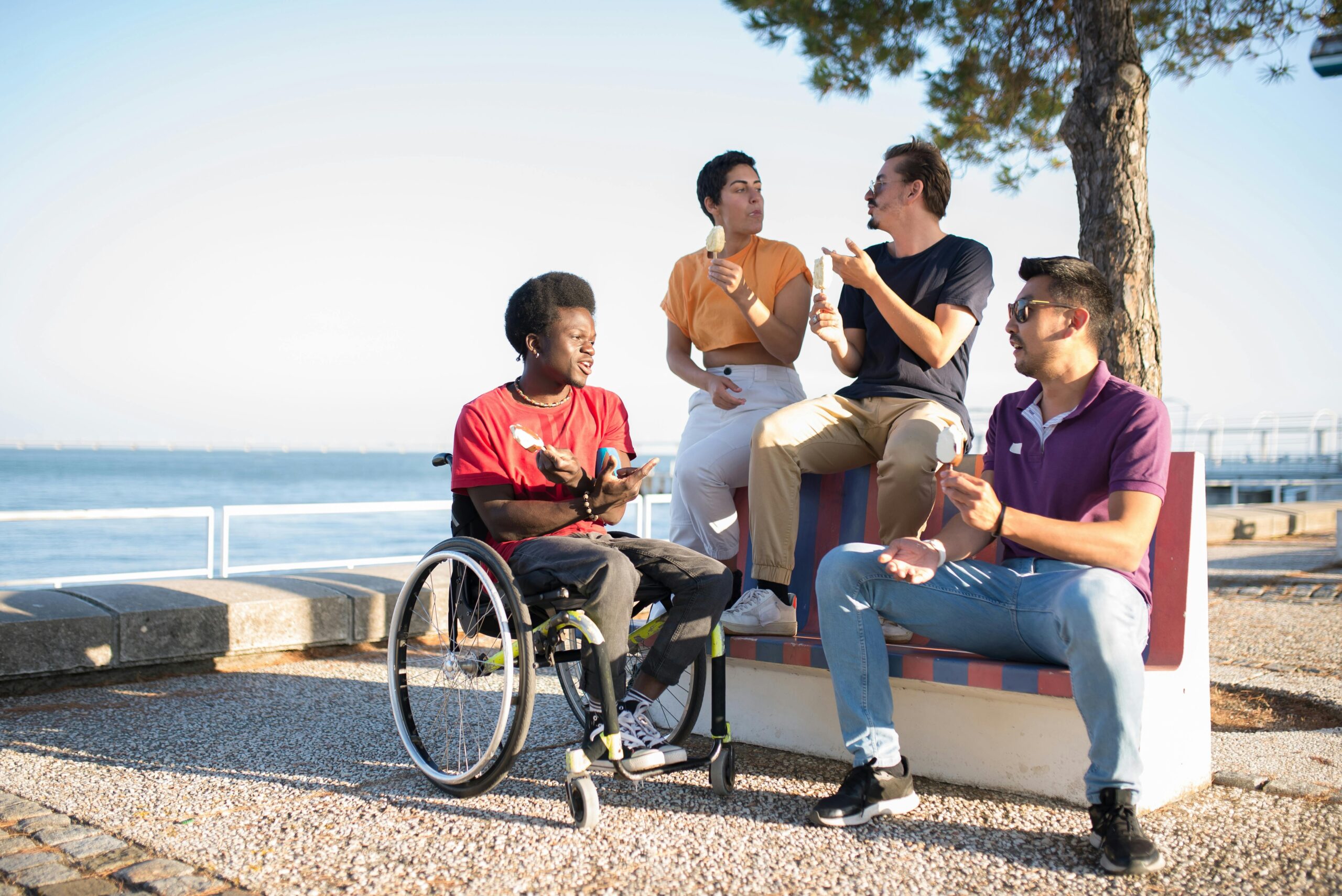 A group of young adults eating ice cream and having a conversation by the sea A group of young adults eating ice cream and having a conversation by the sea