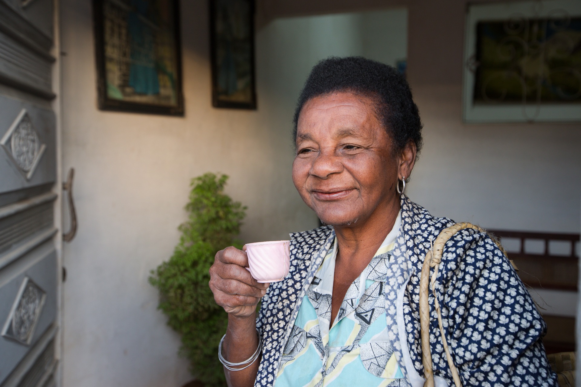 An elderly woman drinking tea and smiling